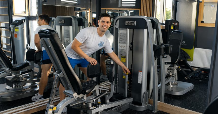 Cosmin Papadopol, instructor de fitness, reglând un aparat într-o sală de fitness din Constanța